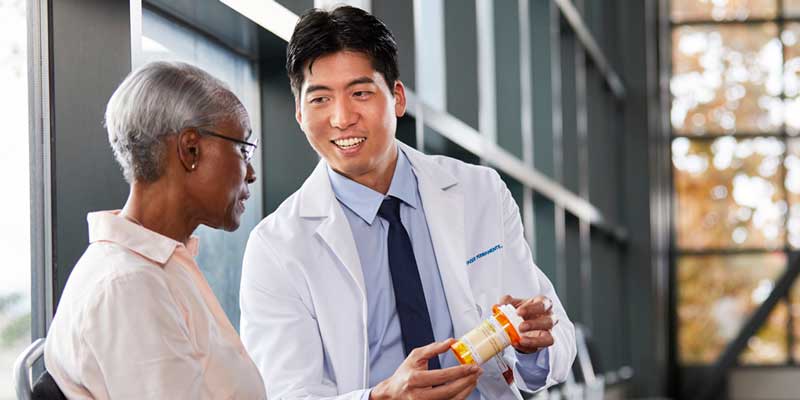 Stock photo: A doctor holding a bottle of pills talking with a patient.