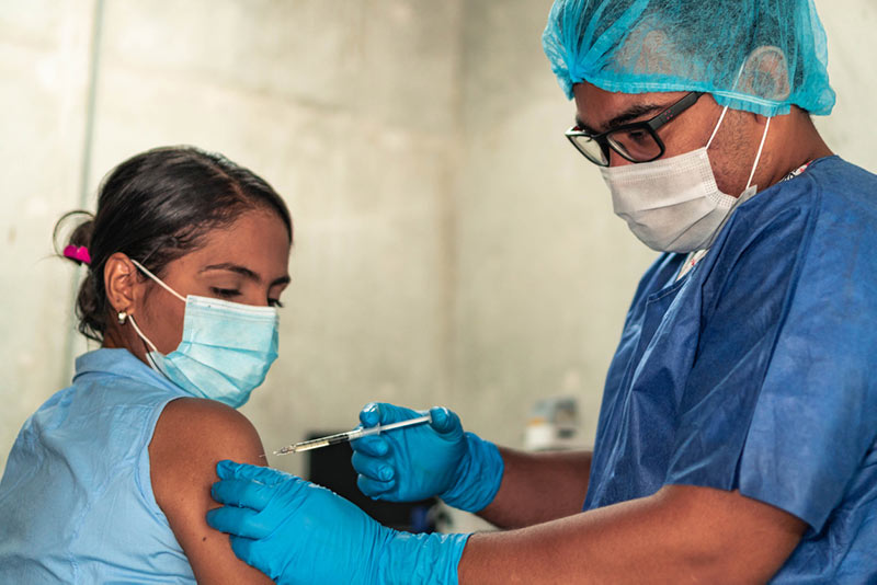 Woman receiving vaccine shot in arm by healthcare clinician