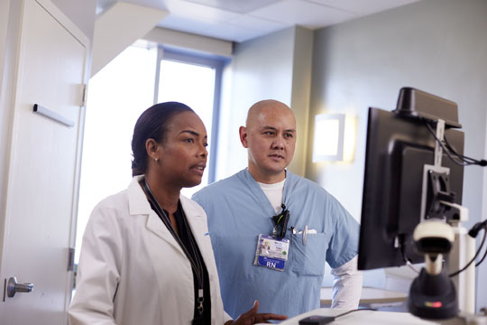 Photo of a clinical nurse going over some paper work with a couple